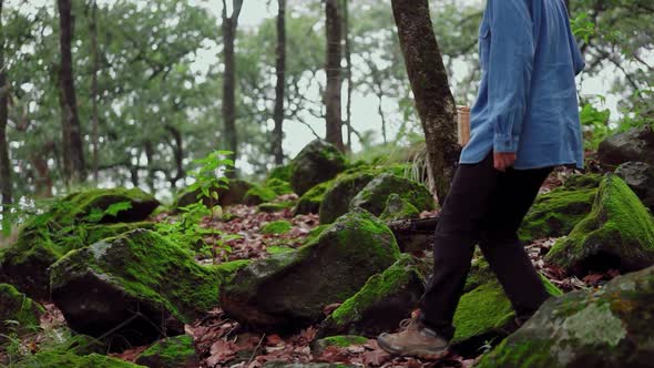 Woman with basket walking through stones in forest