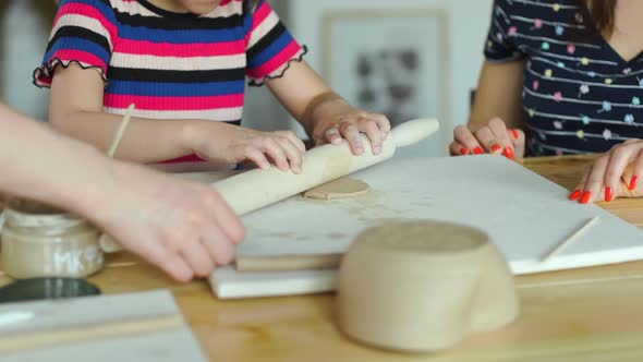 Little Girl Rolling Clay in a Pottery Workshop