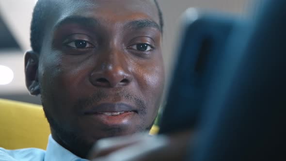 An African American Man Uses a Smartphone To Communicate on the Internet.