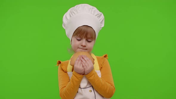 Child Girl 56 Years Old Dressed in Apron Like Chef Cook Eating Tasty Bun on Chroma Key Background