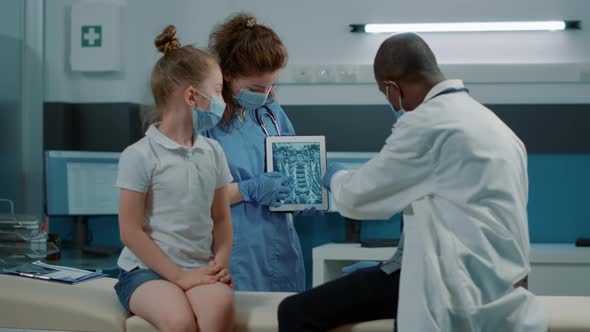 Diverse Medical Team Explaining x Ray Scan Diagnosis to Little Girl