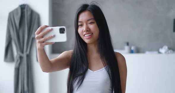 Young Asian Woman Making Video Call Using Smartphone in Bathtub