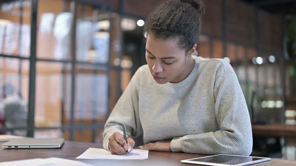 African Woman Writing on Paper at Work