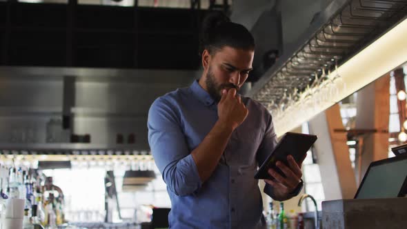 Portrait of mixed race male cafe owner using tablet and looking to camera