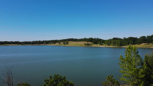 Pushing forward with drone to over the water at a man-made lake.