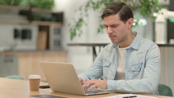 Creative Young Man with Laptop Having Headache
