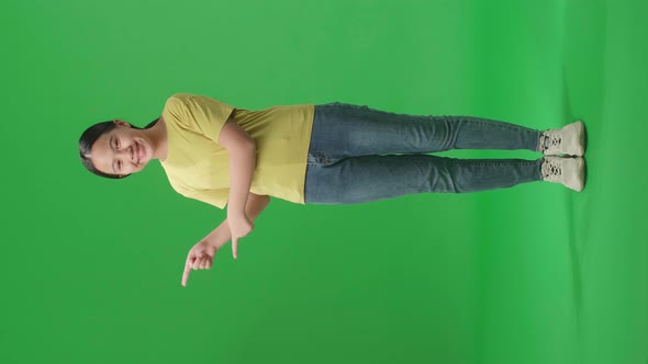 Full Body Of  Asian Kid Girl Smile And Pointing To The Side While Standing In The Green Screen