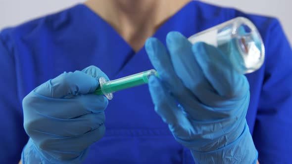 Doctor in Face Mask with Syringe and Medicine