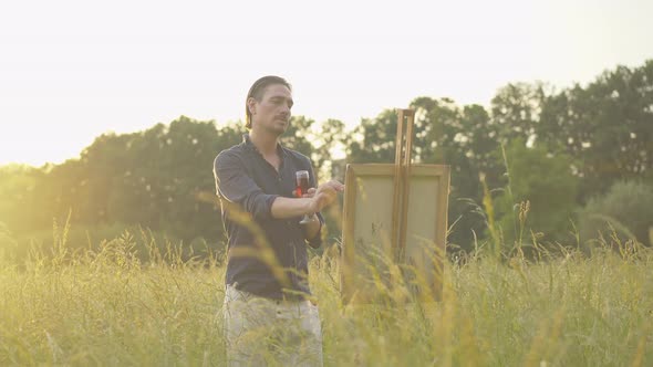Concentrated Caucasian Man Painting Landscape at Sunset. Portrait of Inspired Male Painter with