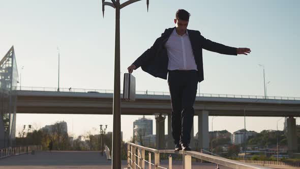 Businessman in Formal Clothes Walks Along Thin Railing and Holds Balance