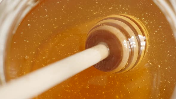 Close-up of spiral wooden honey dipper used in jar slow motion 1080p FullHD footage - Dipped kitchen