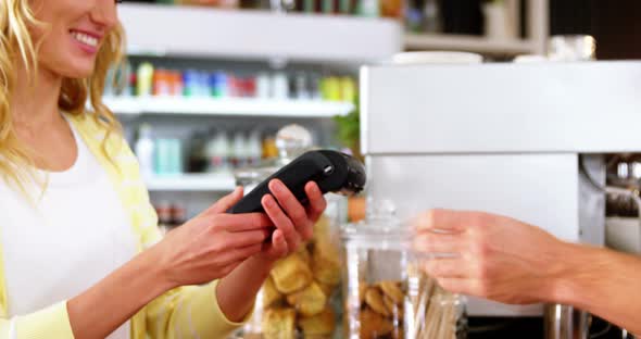 Customer making payment through payment terminal machine at counter