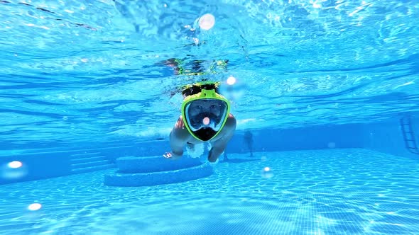 Young boy is swimming underwater in the pool