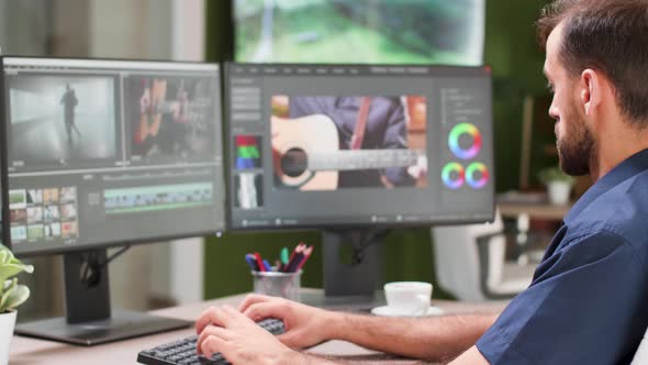 Over the Shoulder Shot of Content Creator Working on His Dual Screen Setup