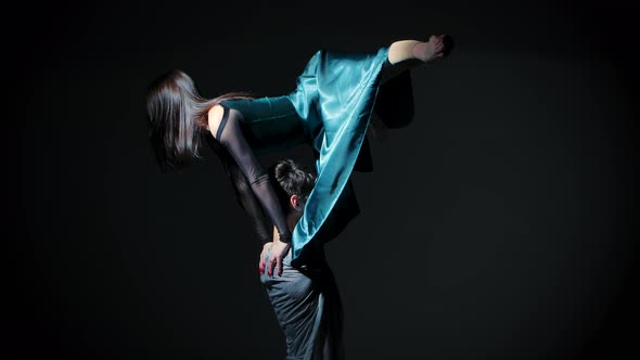 A Couple of Young Dancers Dancing Modern Choreography in the Studio on a Dark Gray Background