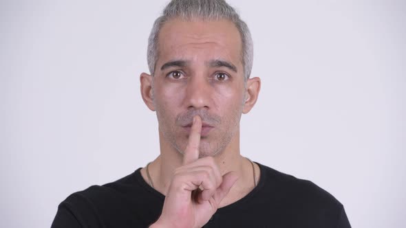 Handsome Persian Man with Finger on Lips Against White Background