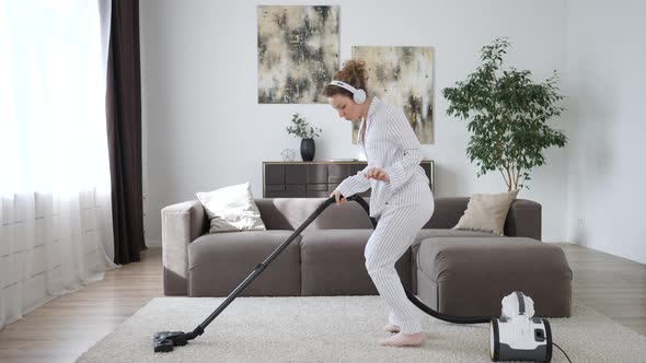 Young Cheerful Woman Dancing With Vacuum Cleaner While Cleaning Living Room.