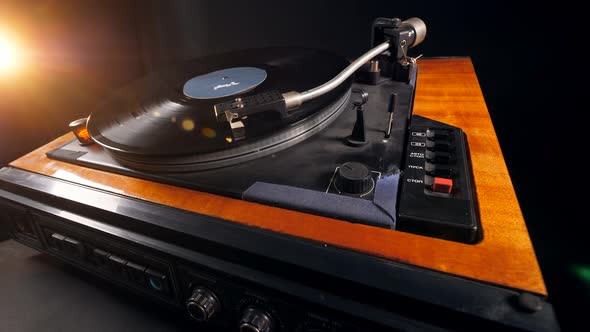 One Person Turns Off a Music Player and Takes a Vinyl Record.