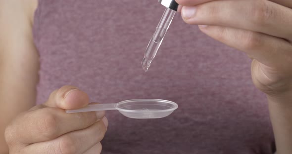 Medicine Drops for Colds Woman with Pipette Drops Syrup in a Spoon