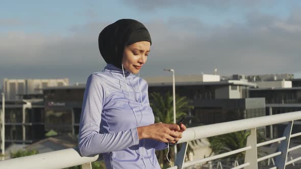 Woman wearing hijab listening music outside