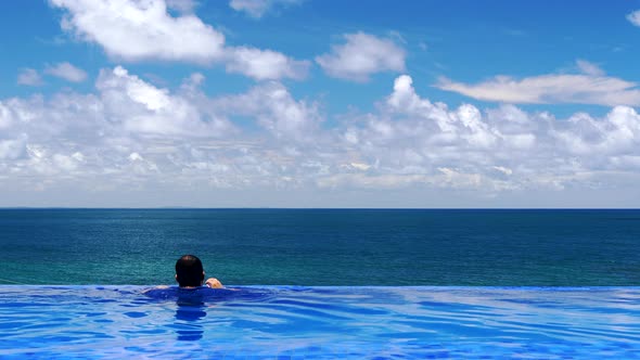 Man in UV t-shirt in swimming pool with infinite edge enjoying summer