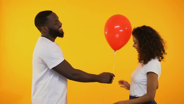 Smiling Afro-American Man Presenting Balloon to Cute Woman, Birthday Gift, Date