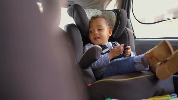 Little Mixed-race Boy Sitting in Baby Seat, Talking To Himself