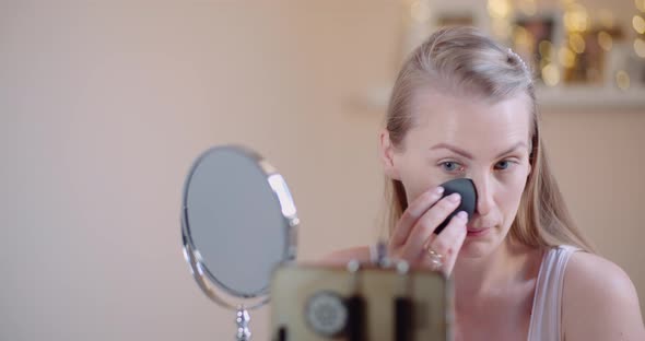 Young Woman Doing Makeup in Front of Mirror at Home