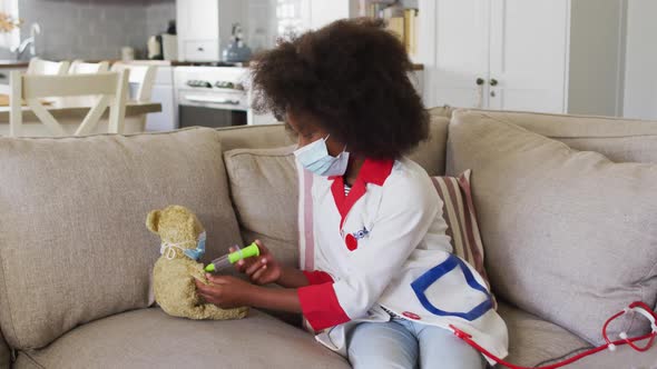 African american girl playing doctor and patient with her teddy bear