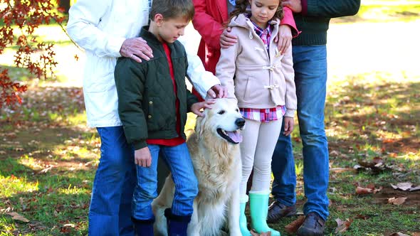 Family standing in the park with their dog