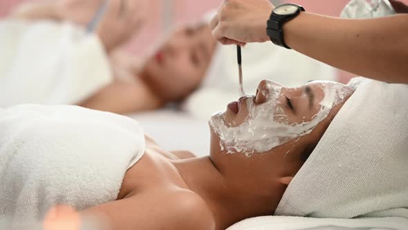 Beautiful Asian woman enjoying applying white mud to her face. at a luxury spa resort