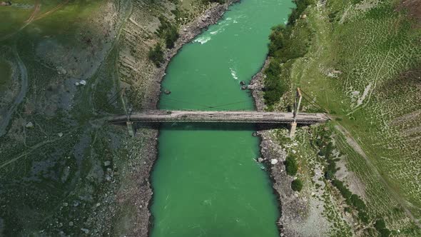 Old suspension ruined bridge on a mountain river. Aerial view