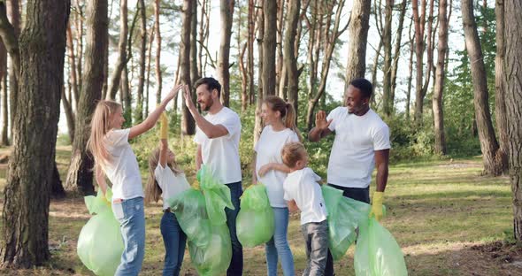 Team of Adults and Kids Which Giving High Five Each Other After Collected Rubbish Into Plastic Bags