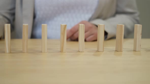 Hand of a Business Woman Stopping Falling Dominos to Prevent a Total Collapse and Establish