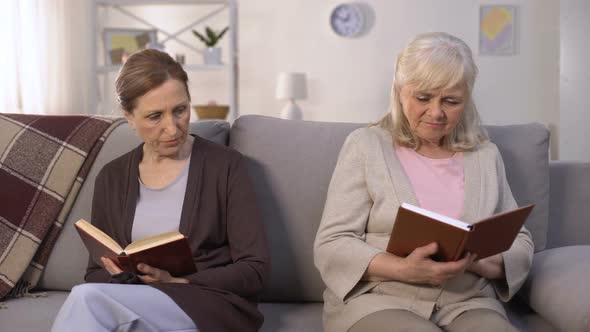 Two Envious Old Women Reading Books Sitting on Hall of Nursing Home, Rivalry