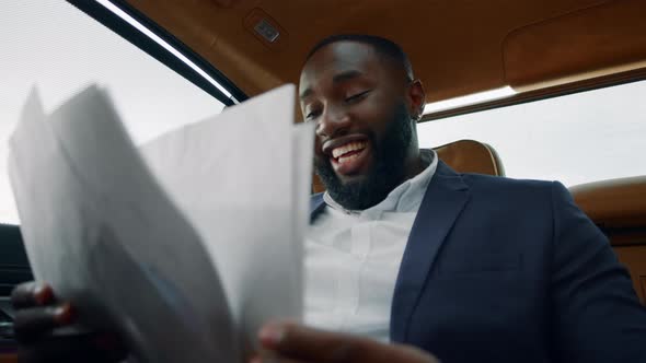 Closeup Man Reading Documents at Car. Businessman Enjoying Success at Backseat