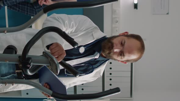 Vertical Video Portrait of Physician Using Stationary Bicycle to Help Patients