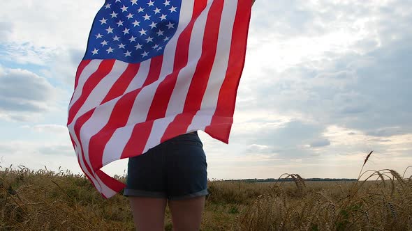 Happy Patriotic Young Woman Holds the US Flag and Runs Across the Field