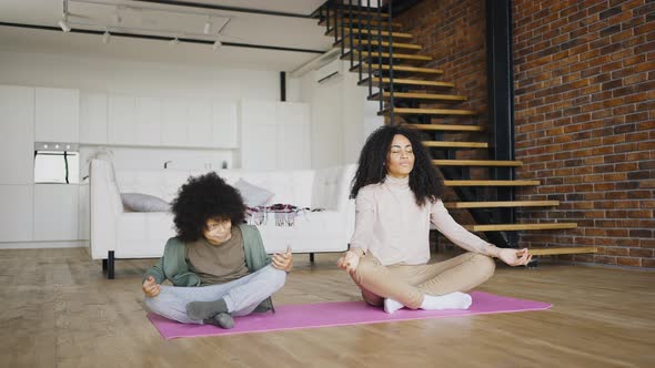 African American Young Mother Meditates in the Lotus Position