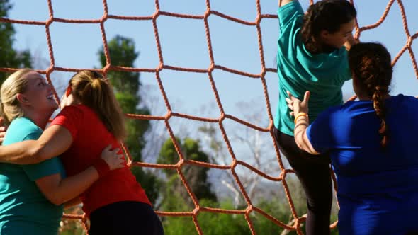 Women practicing net climbing during obstacle course