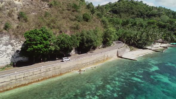 Aerial view of white car driving on coastline in Oslob, Philippines.