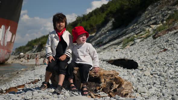 Two Boys Children in Fashionable Clothes Walk on the Stone Sea Beach