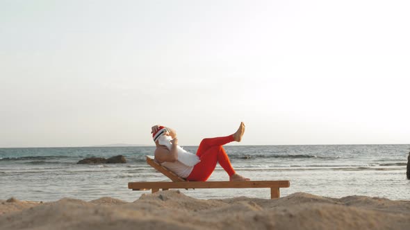 Funny Santa Claus Sunbathes. Santa Lies on Wooden Lounger on Beach By the Sea and Drinks a Delicious