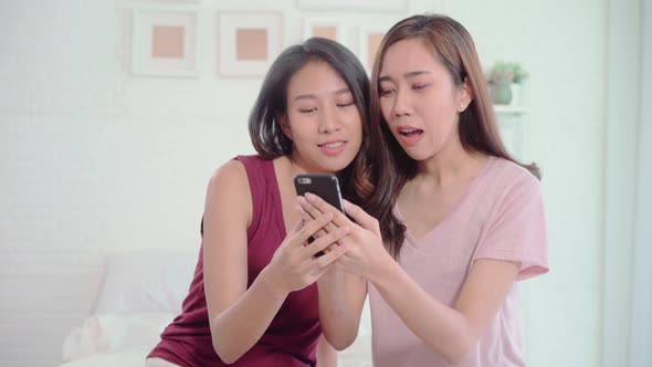 Young Asian women lesbian using smartphone checking social media in bedroom.
