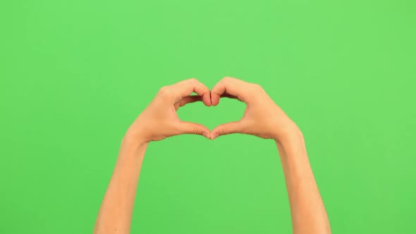 Closeup View of Female Hand Making Heart Shape Gesture Isolated on Green Screen Chromakey Background