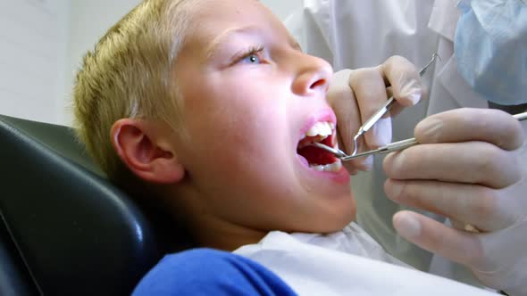 Dentist examining a young patient with tools