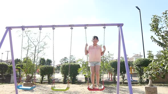 Cute Asian Girl Playing Swing In The Park