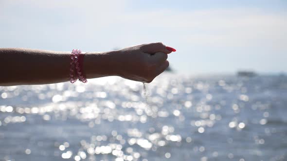 Hand of Woman Holding Handful of Sand