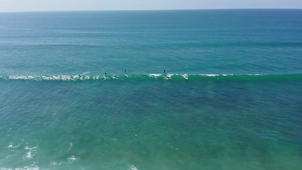 Aerial shot of surfers riding waves on the West Coast of America in summer