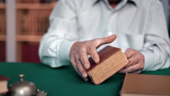 Closeup Elderly Male Hands Taking Antique Book Reading at Desk in Library